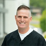 Smiling male dentist in black scrubs standing outdoors