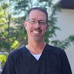 Smiling female dentist in professional attire against light background
